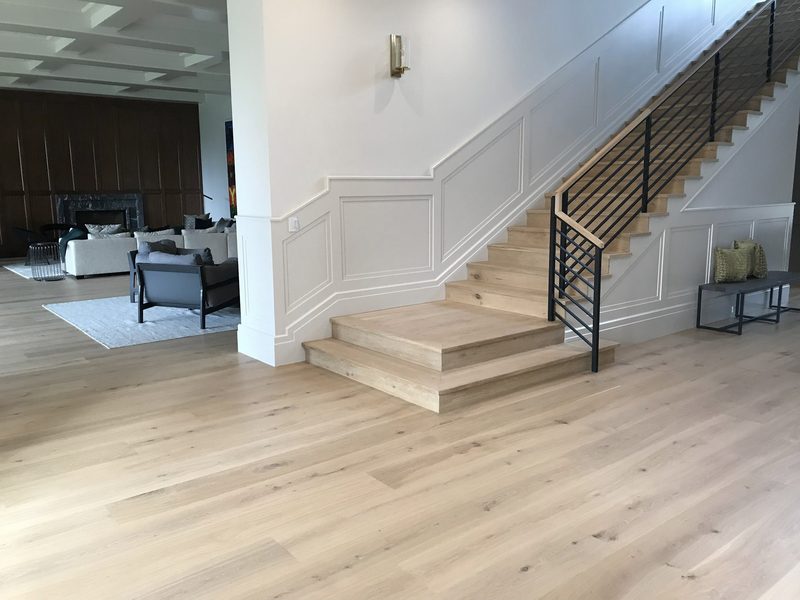 Light oak floor through an open living area and staircase